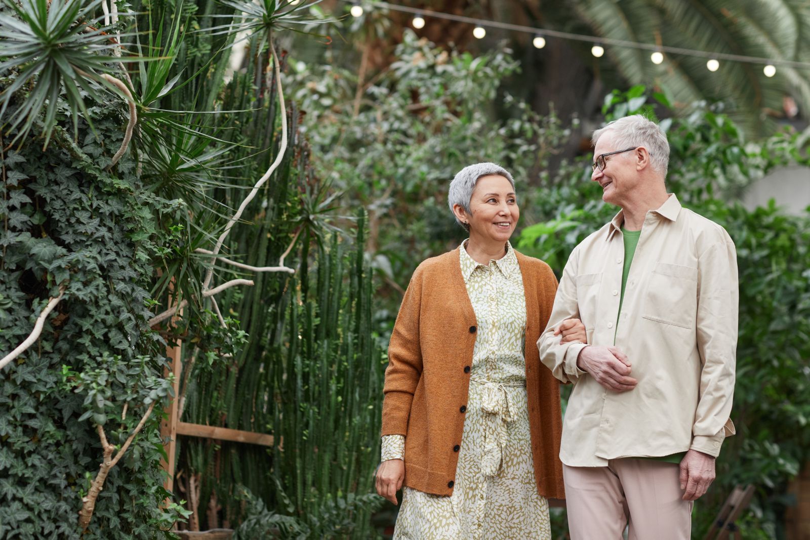 A couple in their sixties walking together through a garden